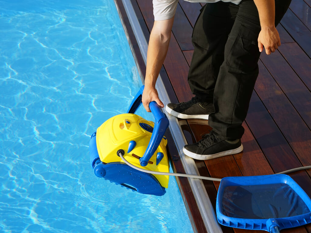 Man using pool cleaning tool on in ground pool