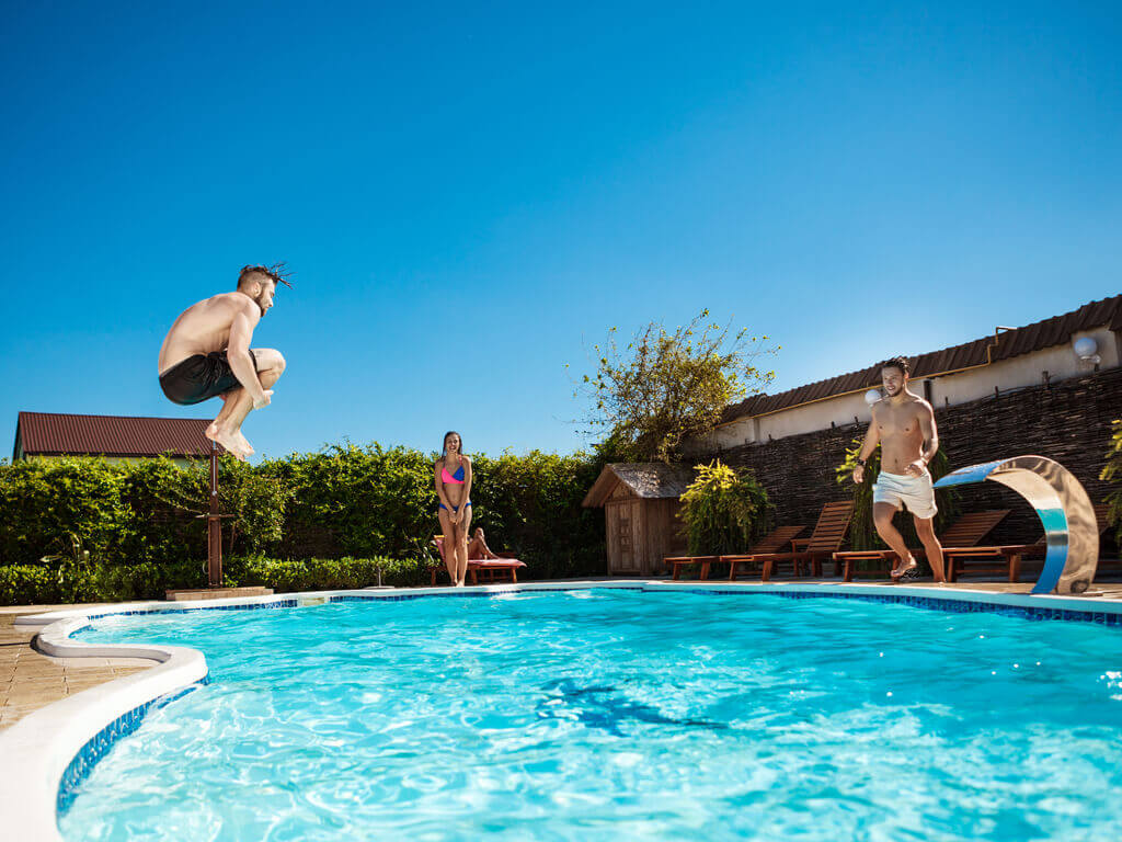 friends jumping into a swimming pool