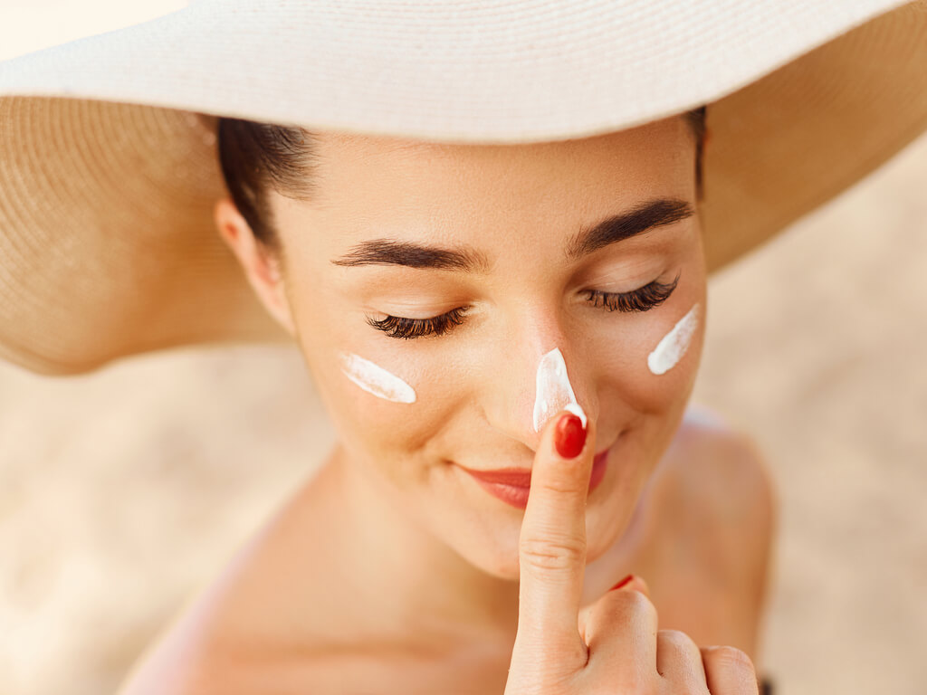 woman putting sunscreen on face